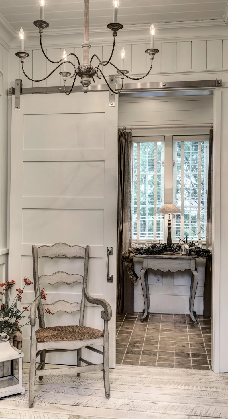 Habersham ladderback chair with Visual Comfort antique wood chandelier Design Thought: With the outdoor view through the window perfectly centered in the doorway, one can add a rustic Dovetail accent table and lamp to stylize the bathroom entry.