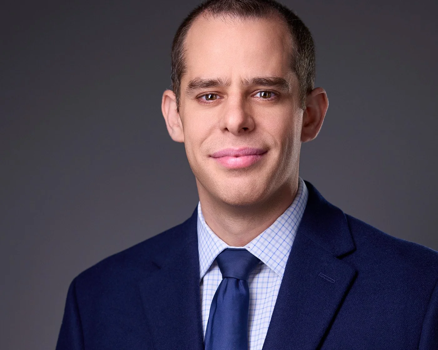 Portrait of Craig Rosenblum wearing a suit in front of a gray background.