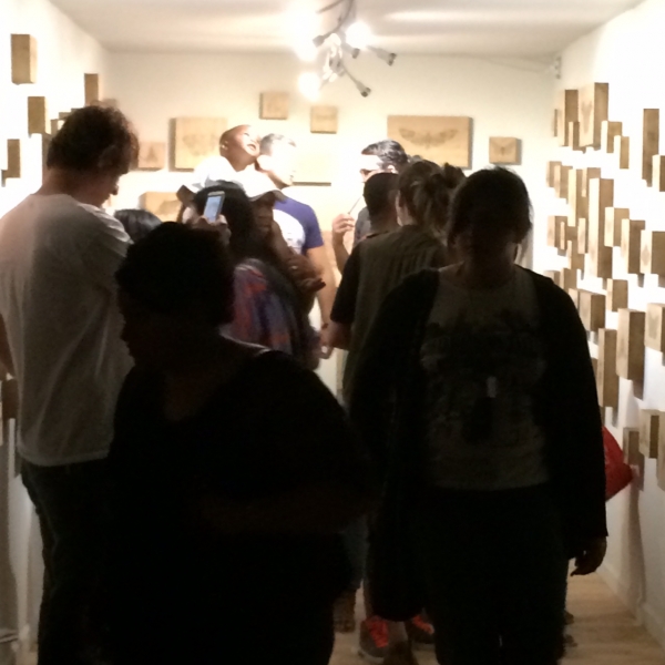  People enjoying Lexie's installation of her wood-burned moth drawings, First Friday, 5-1-15. Photo credit-William LeGoullon 