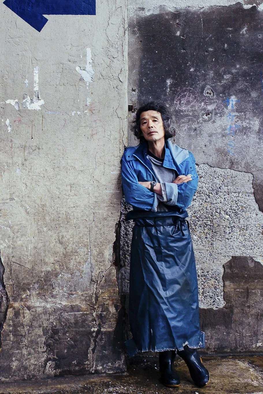 Tsukiji Market worker rests against wall in Tokyo, Japan