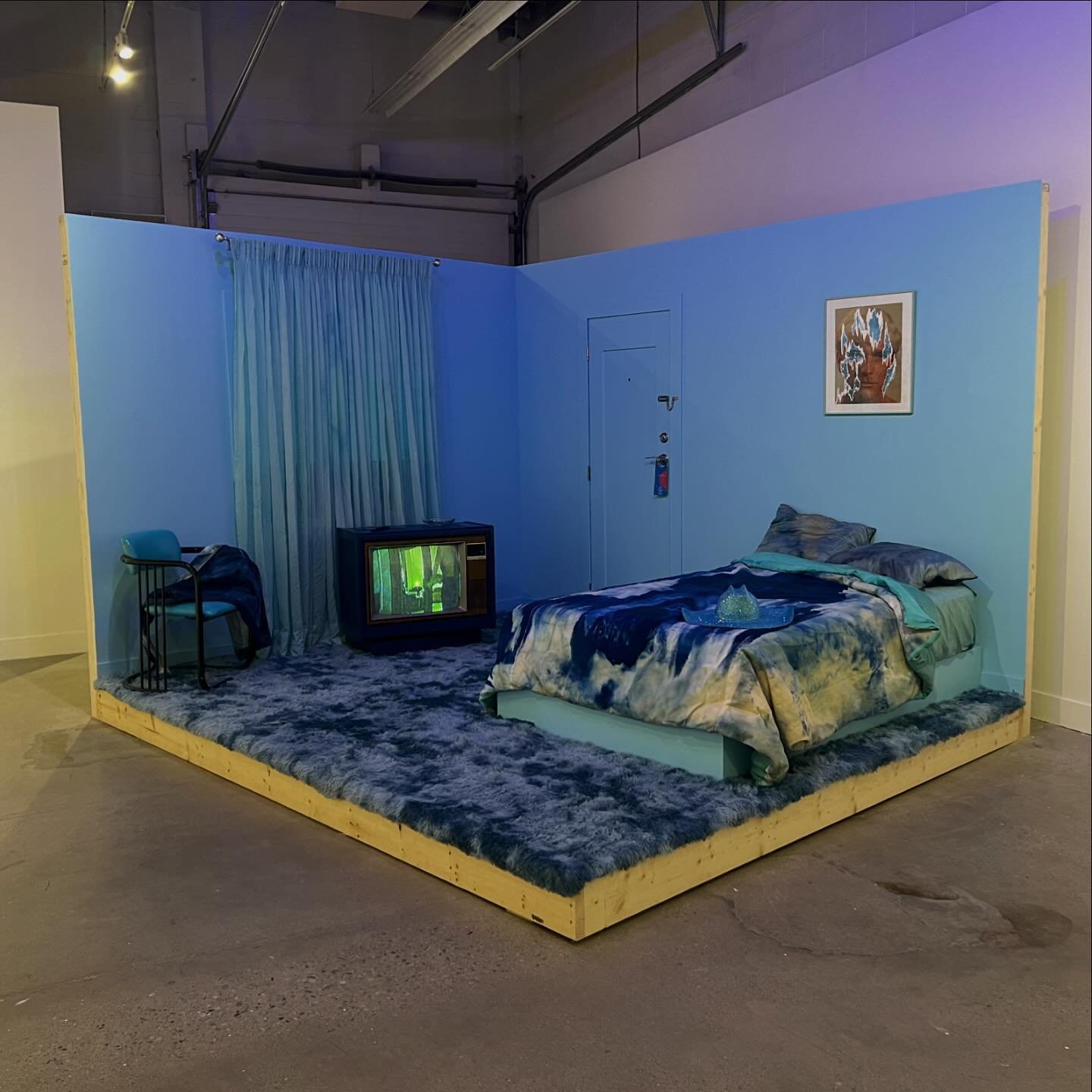 FANTASY SEQUENCE (blue fantasy motel) is the set of a fictional pornographic film featuring various collected material and handmade objects including bedding, denim jacket, cowboy hat, and a take away motel keychain. This installation was created as 