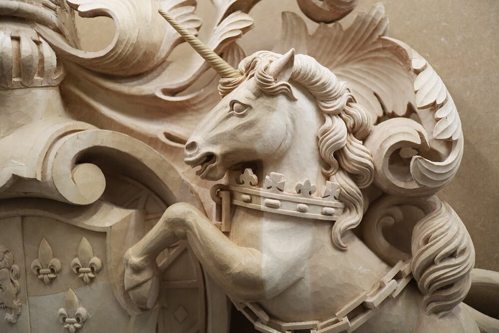 A close up of the unicorn from the King George III coat of arms. Heraldic unicorns differ from horses (besides the horn) in often having cloven hoofs and a long bare tail with a tufted end like a lion, rather than a traditional horse tail. They&rsquo