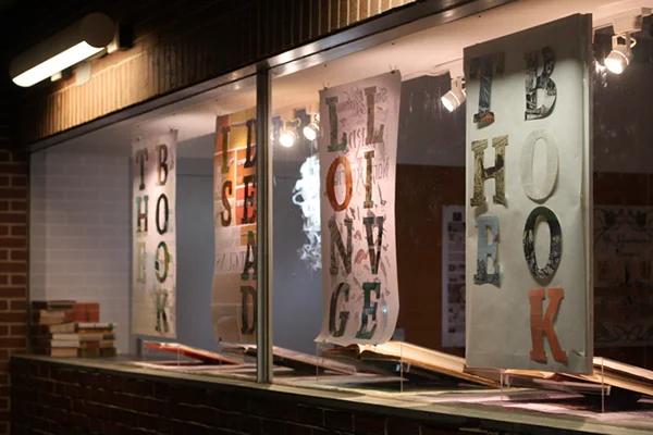  The window space also doubled as an advertisement: Our group also lasercut the letters of the exhibit name from pages of old books and affixed them to the back of our posters. 