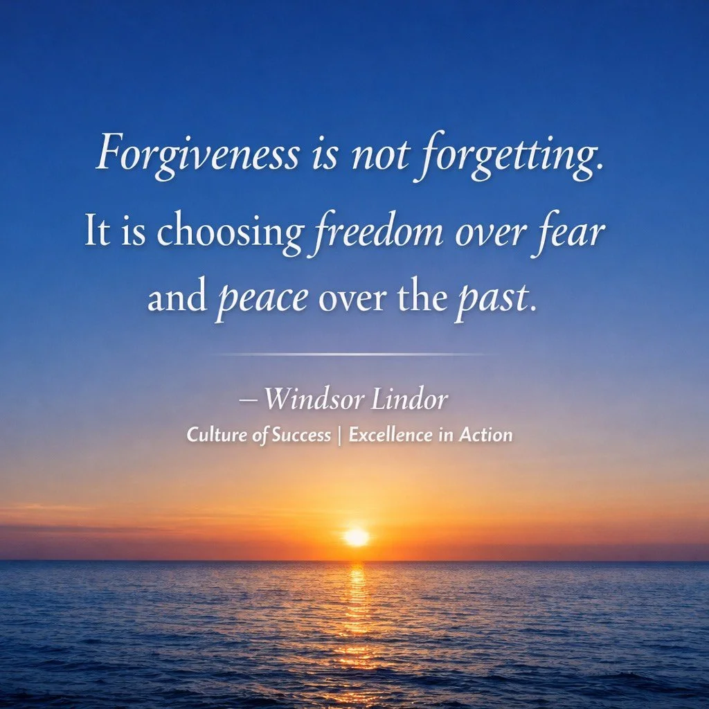Sunset over a calm body of water with a sandy beach and grassy dunes in the foreground.