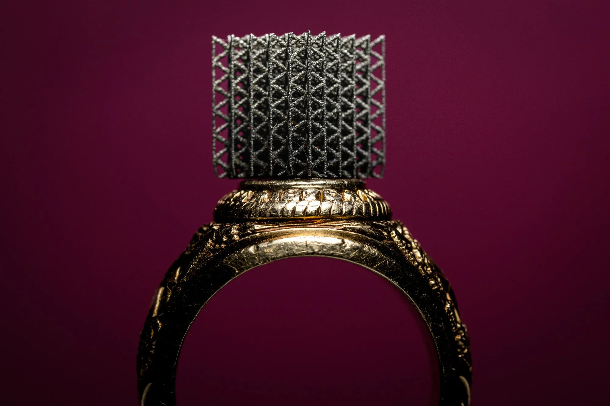  Close-up of a Texas A&amp;M Aggie class ring on a maroon background with a 3D Printed material 