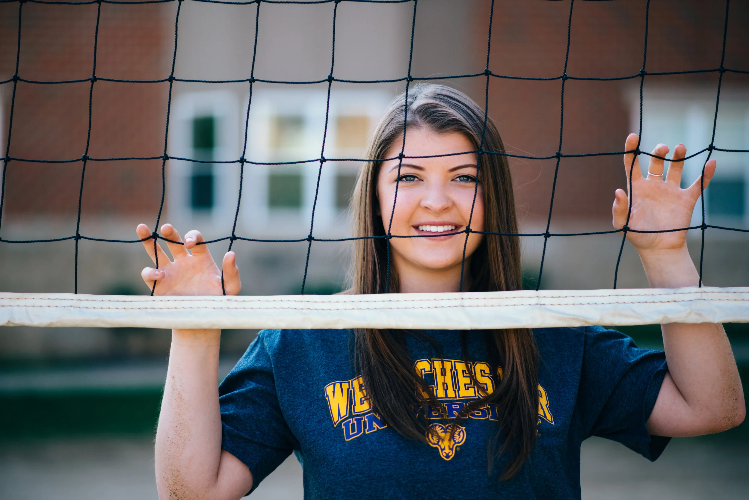 high school senior model behind volleyball net with Westchester University college shirt