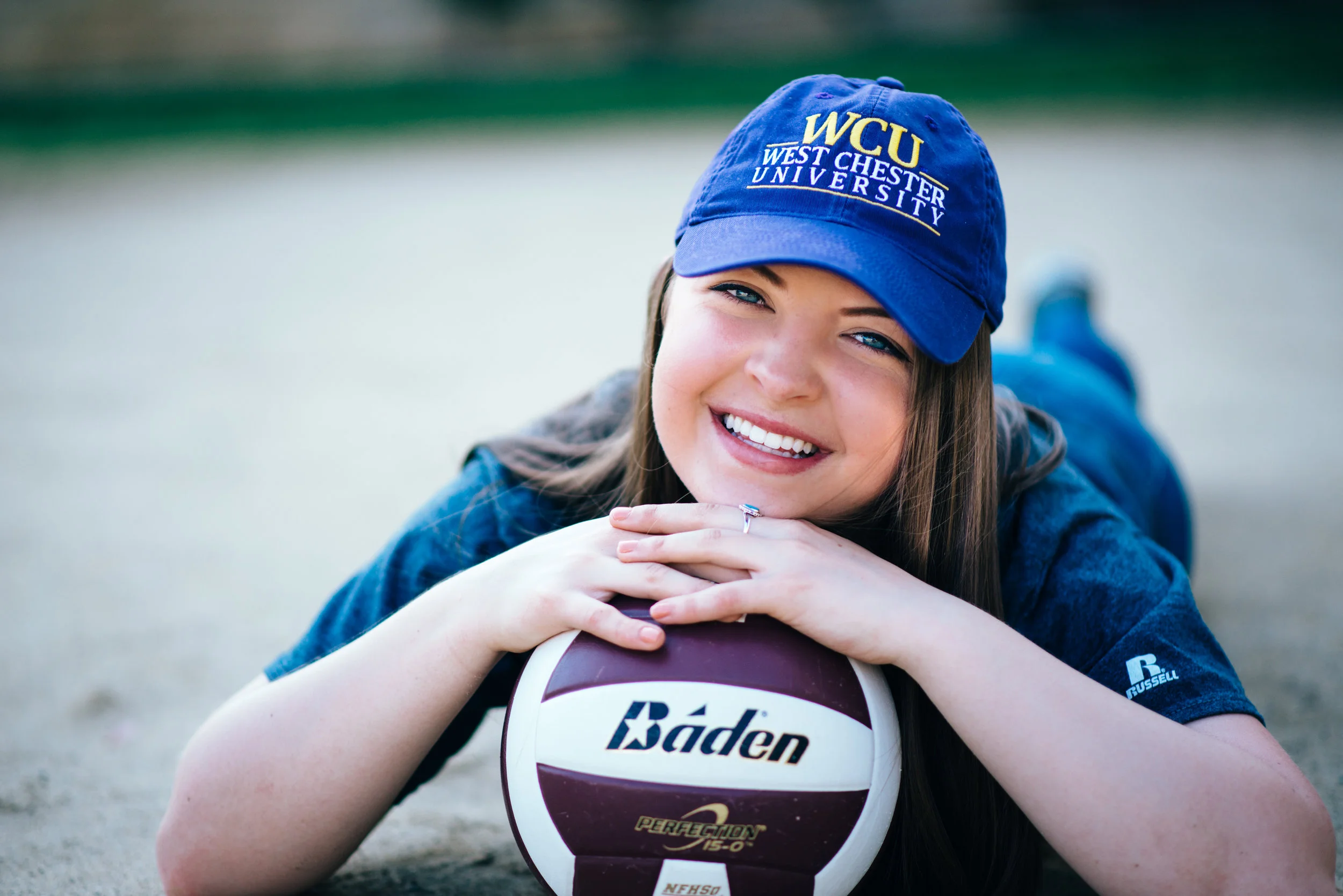 high school senior model posed with purple volleyball wearing a west chester university college hat