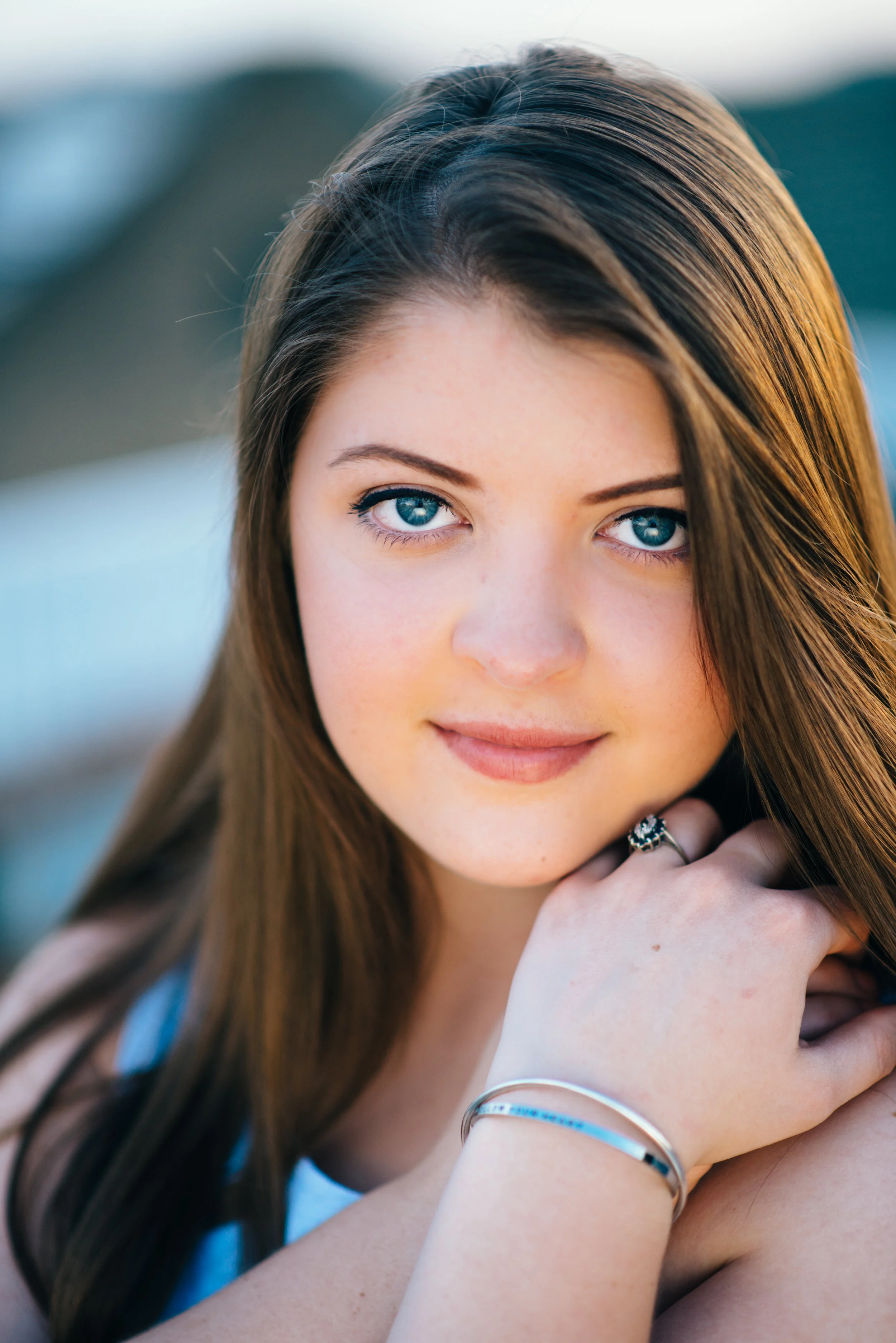 headshot using reflector of high school senior model in light blue shift dress standing on top of parking garage overlooking city of Indiana PA