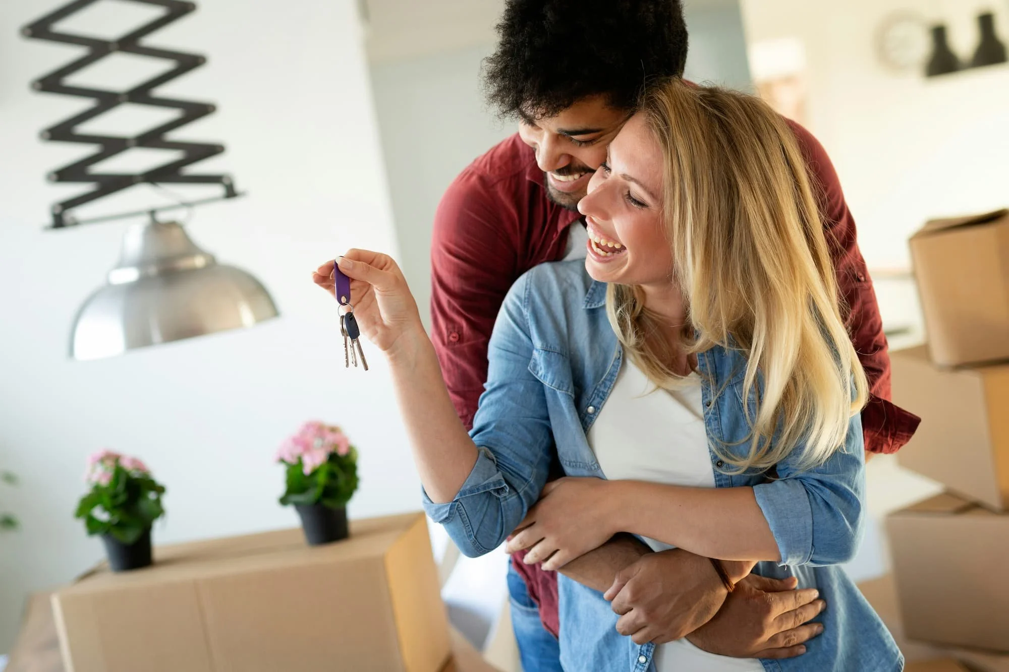 Happy couple celebrating moving into new home, with woman holding keys and both smiling.