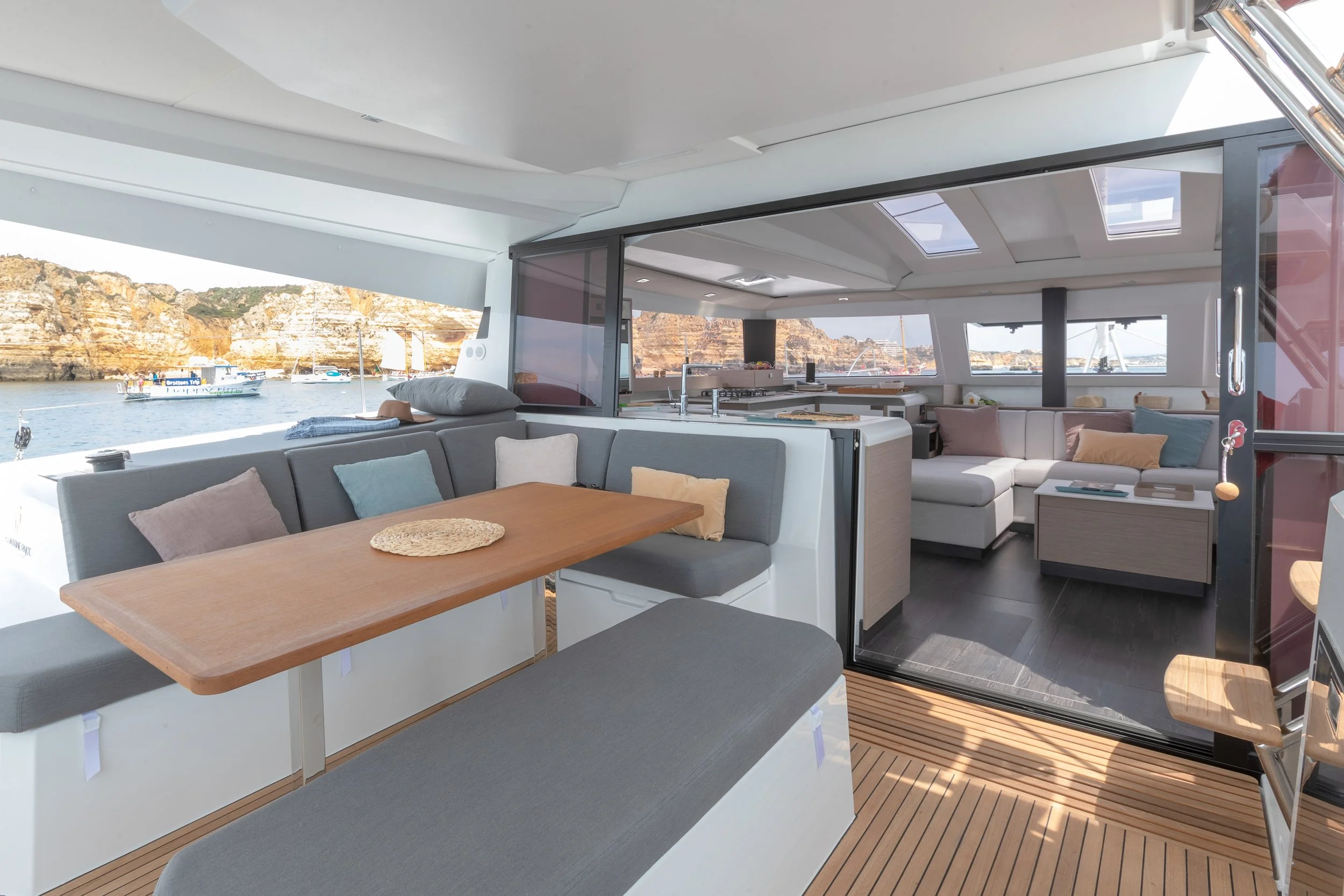 Interior of a luxury yacht with a seating area, dining table, and view of water and boats through windows