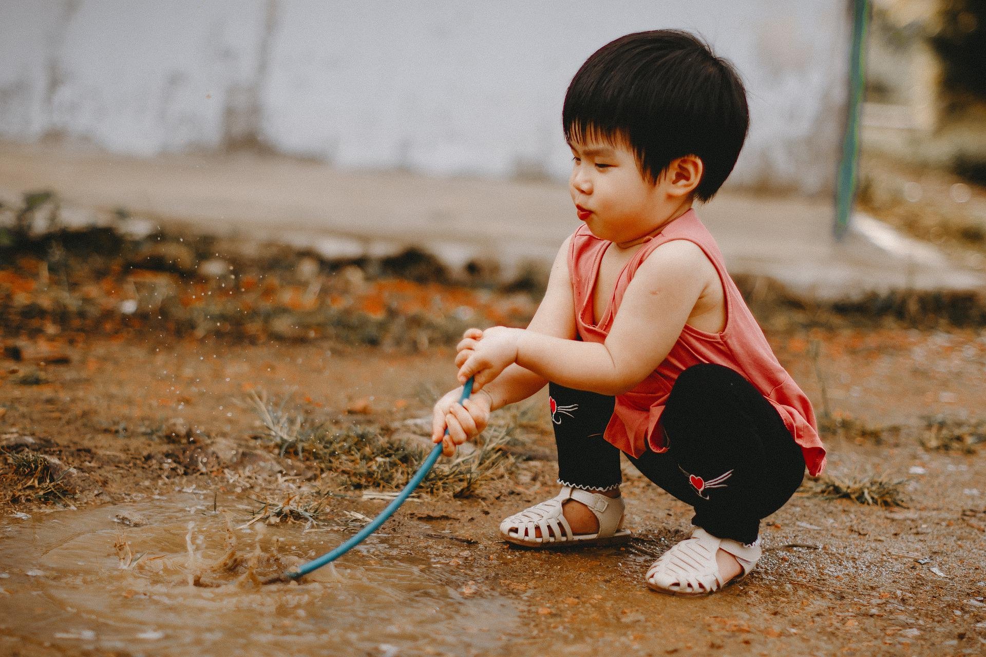 A toddler plays in mud.