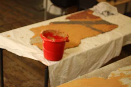 Application in sections of appropriately coloured mortar to the back of the mosaic