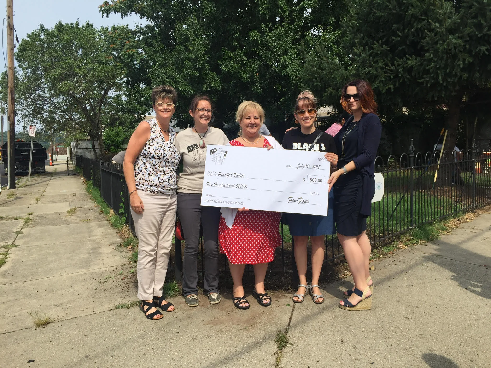 The FemFour presenting a check from our proceeds of sales from Still They Persist , to Sheryl Rajbahndari of Heartfelt Tidbits.