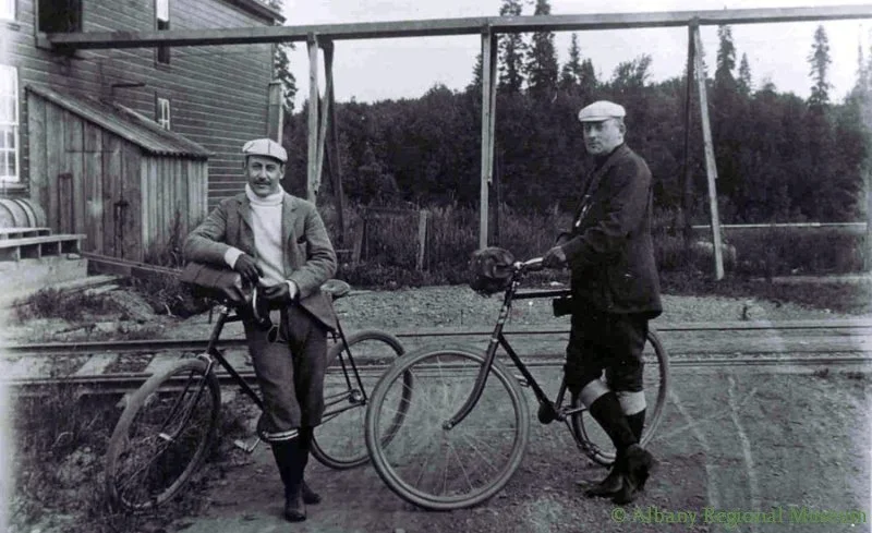 Robert Albert Bertram Veal and Percy R. Kelly at Water Ave. plant of Veal Chair Factory and their bikes. Kelly became a Circuit Court Judge and later a Justice on the Oregon Supreme Court. c. 1900.