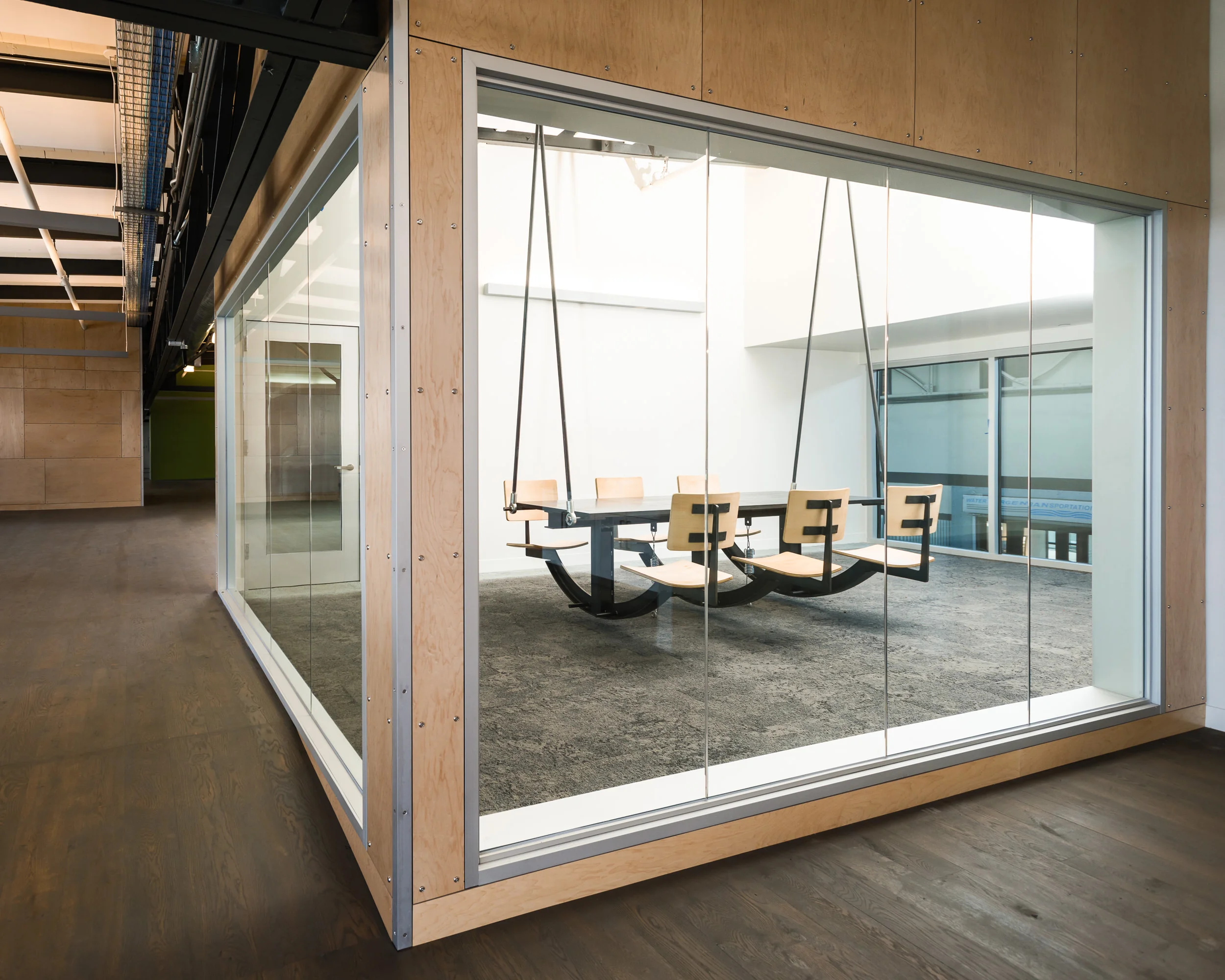 Lundberg designed and built a swinging conference table and a reception booth for Autodesk's office in San Francisco. Based on Autodesk's request for a conference table "emblematic of collaborative use", the conference table is a hanging fixture that moves with the movements of its participants, i.e. "we're all in this together". These photos document the on-site assembly process. The materials were primarily wood and blackened steel. During construction, before spring dampers were installed, staff would come periodically to "give it a go". A: Lundberg Design