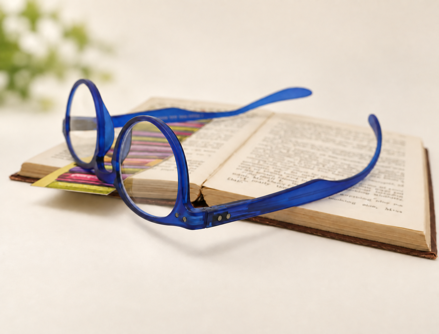 Blue Hangover Panto long-arm reading glasses resting upside down on an open book