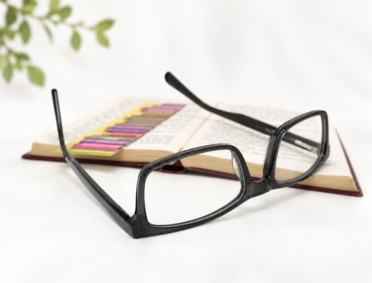 Santana charcoal grey reading glasses beside an open book