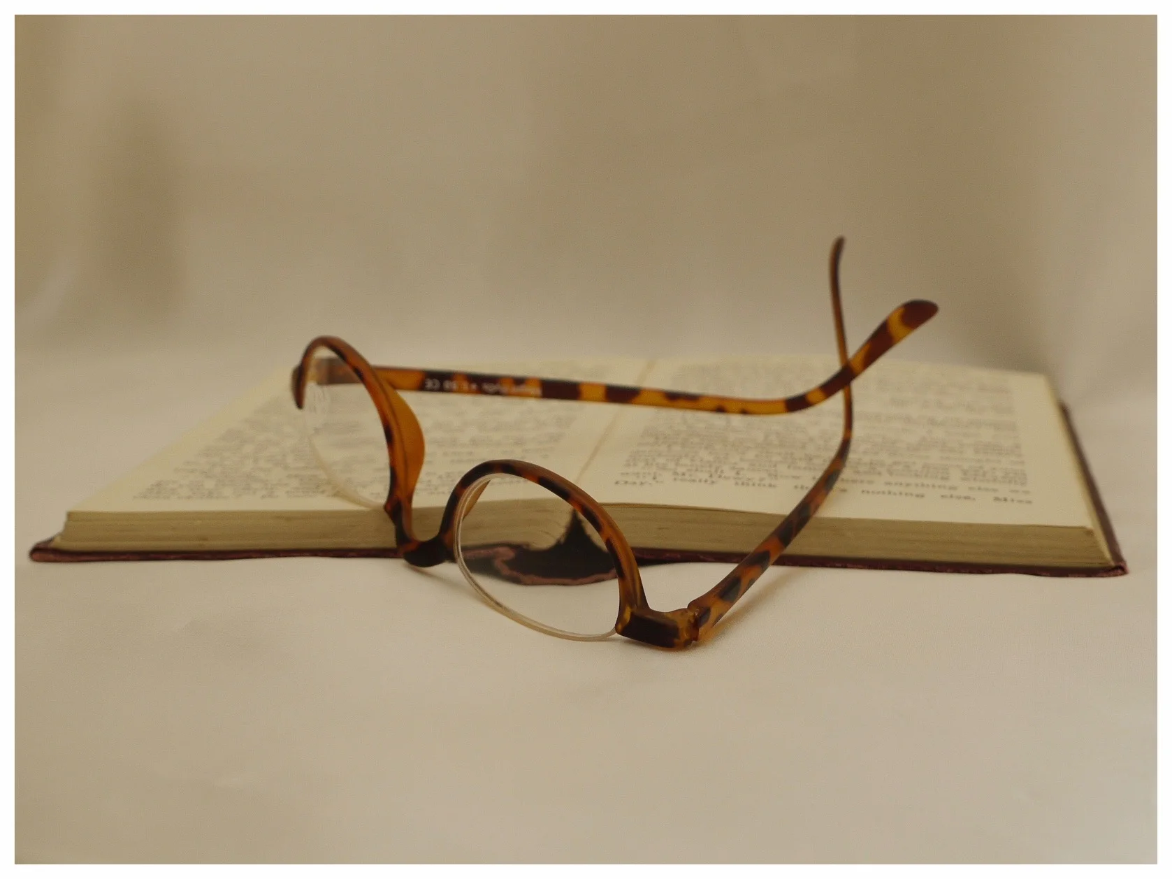 pair of half-eye reading glasses resting on a book