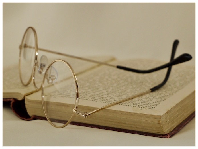 gold, round-eye reading glasses, on book