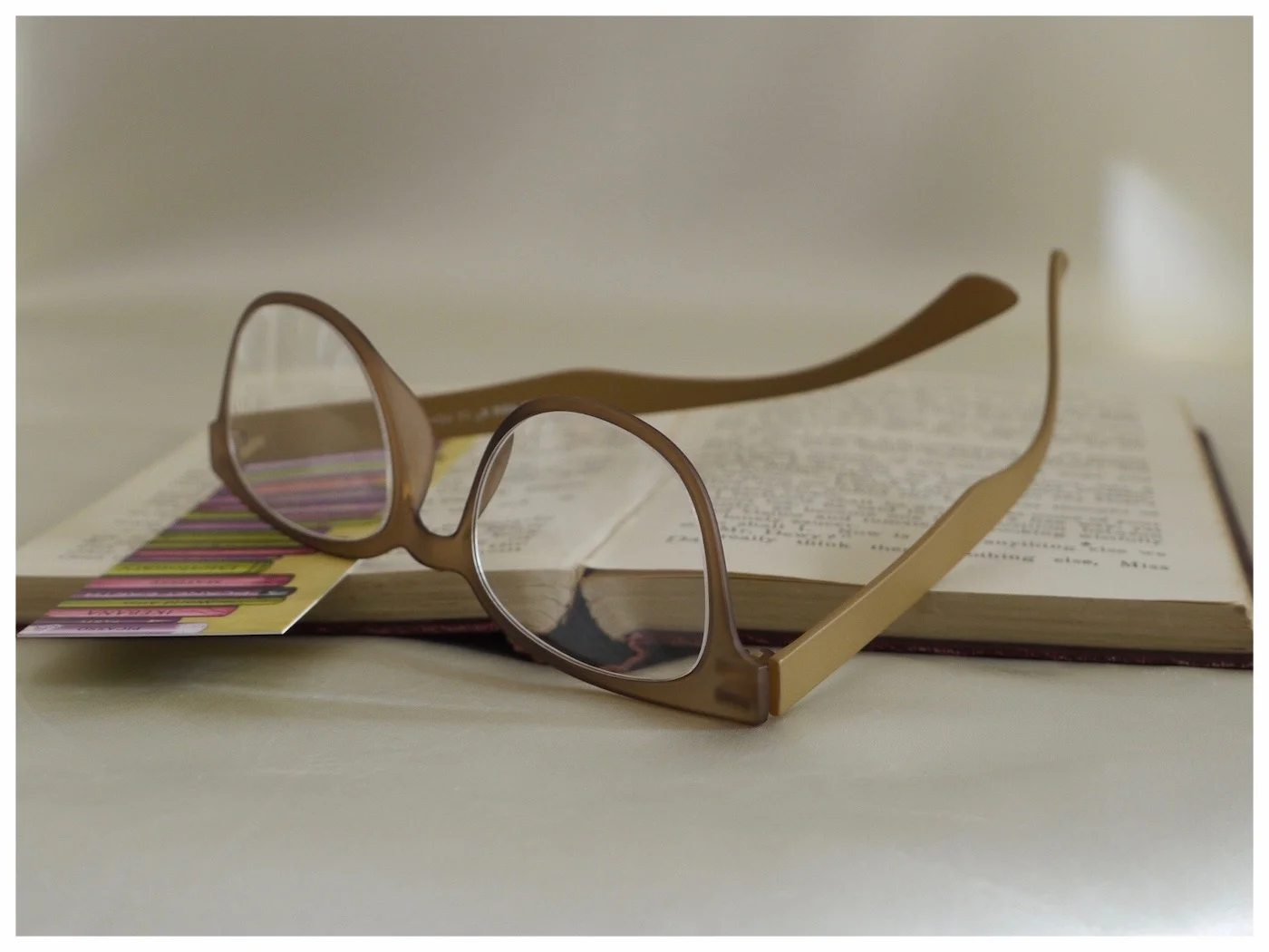 pair of brown coloured, lightweight reading glasses on an open book