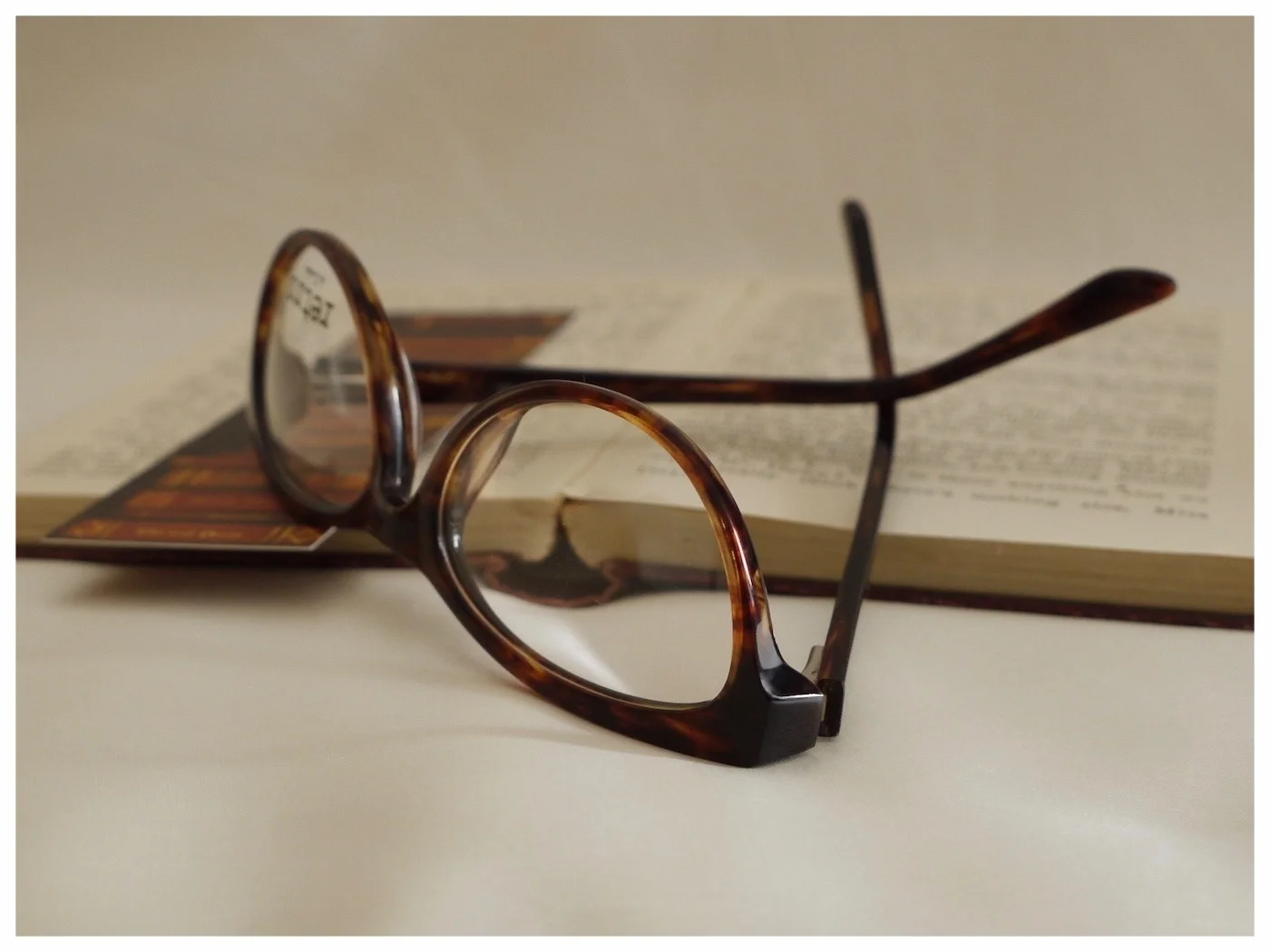 pair tortoiseshell reading glasses on an open book