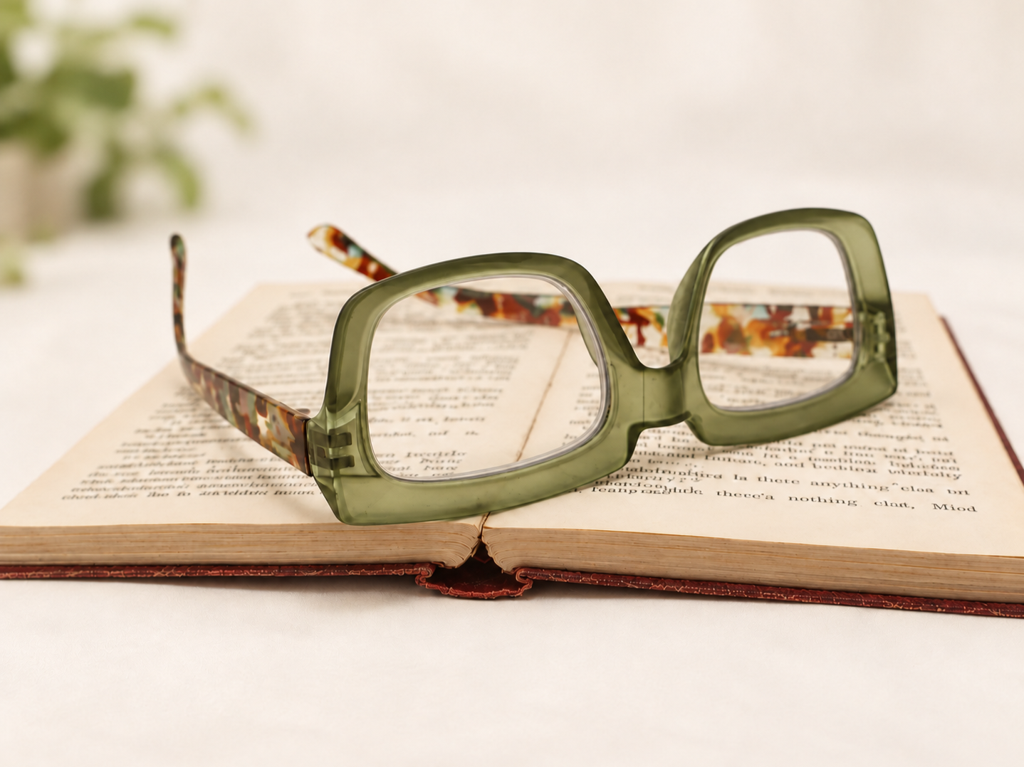 Ikaly Seoul green reading glasses resting upside down on an open book