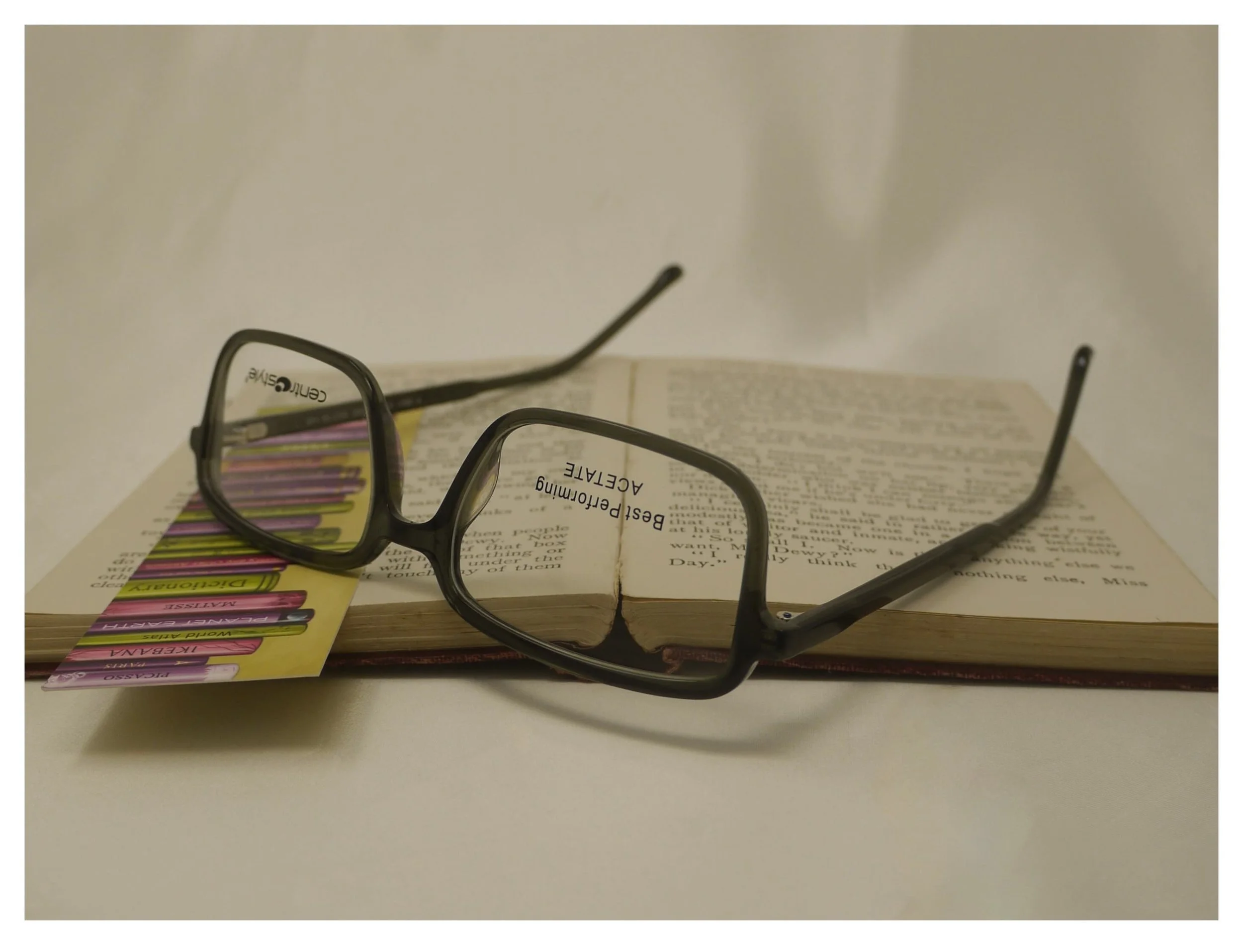 Alternate inverted angle of the F0641 dark green reading glasses on a book, showing hinge and temple construction