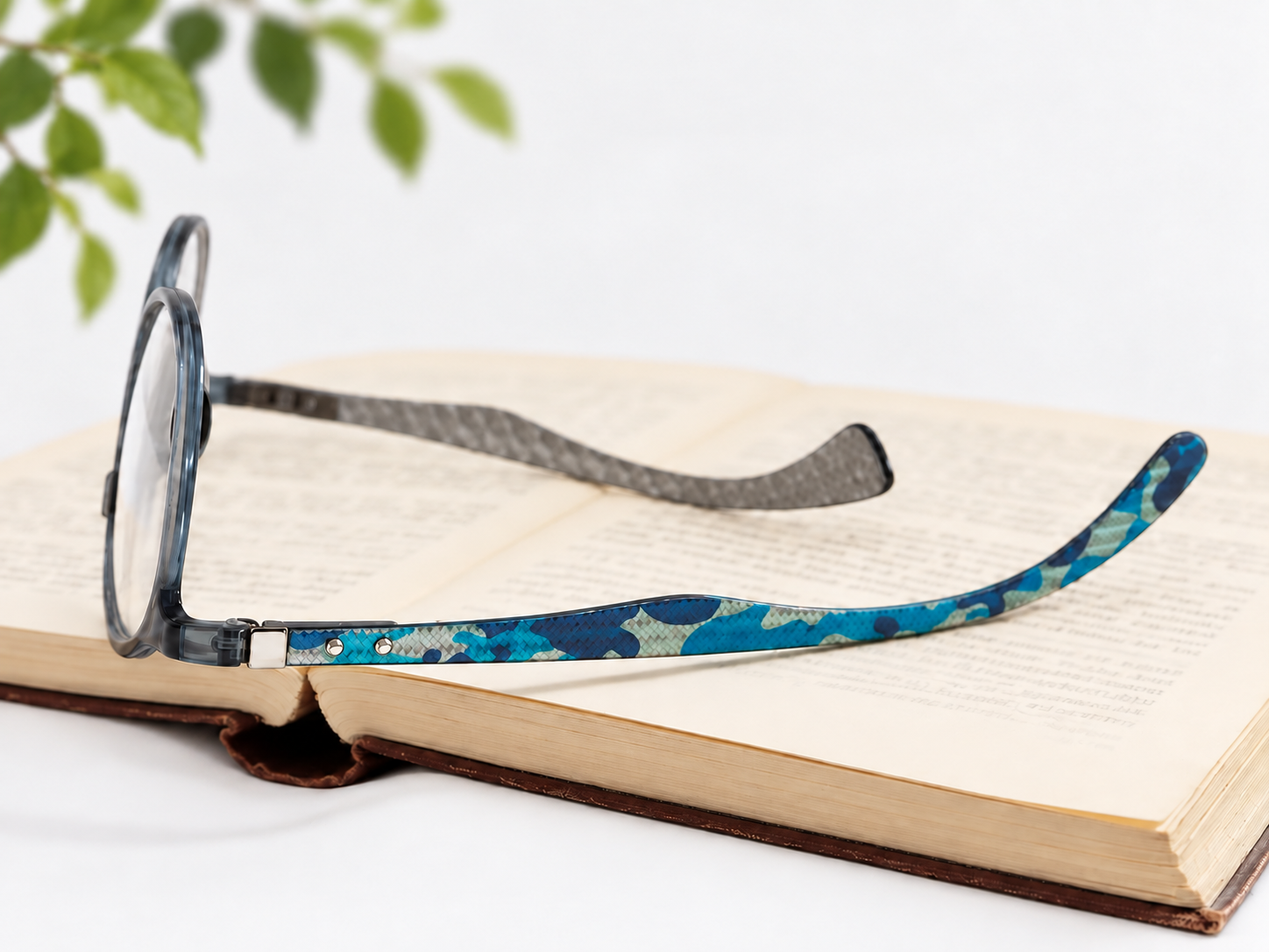 Jacob Stone Sky 16049 blue reading glasses resting on an open book