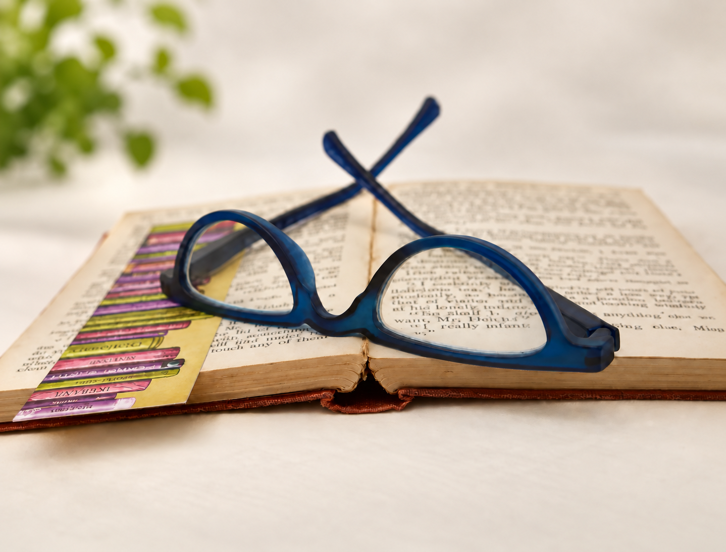 L40 oval tortoiseshell reading glasses positioned in front of an open book