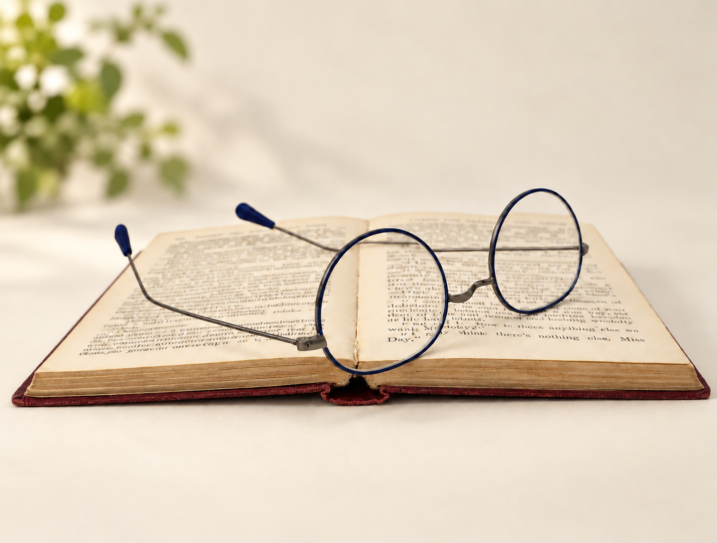 Lennard blue and gunmetal reading glasses displayed open across the pages of a vintage book