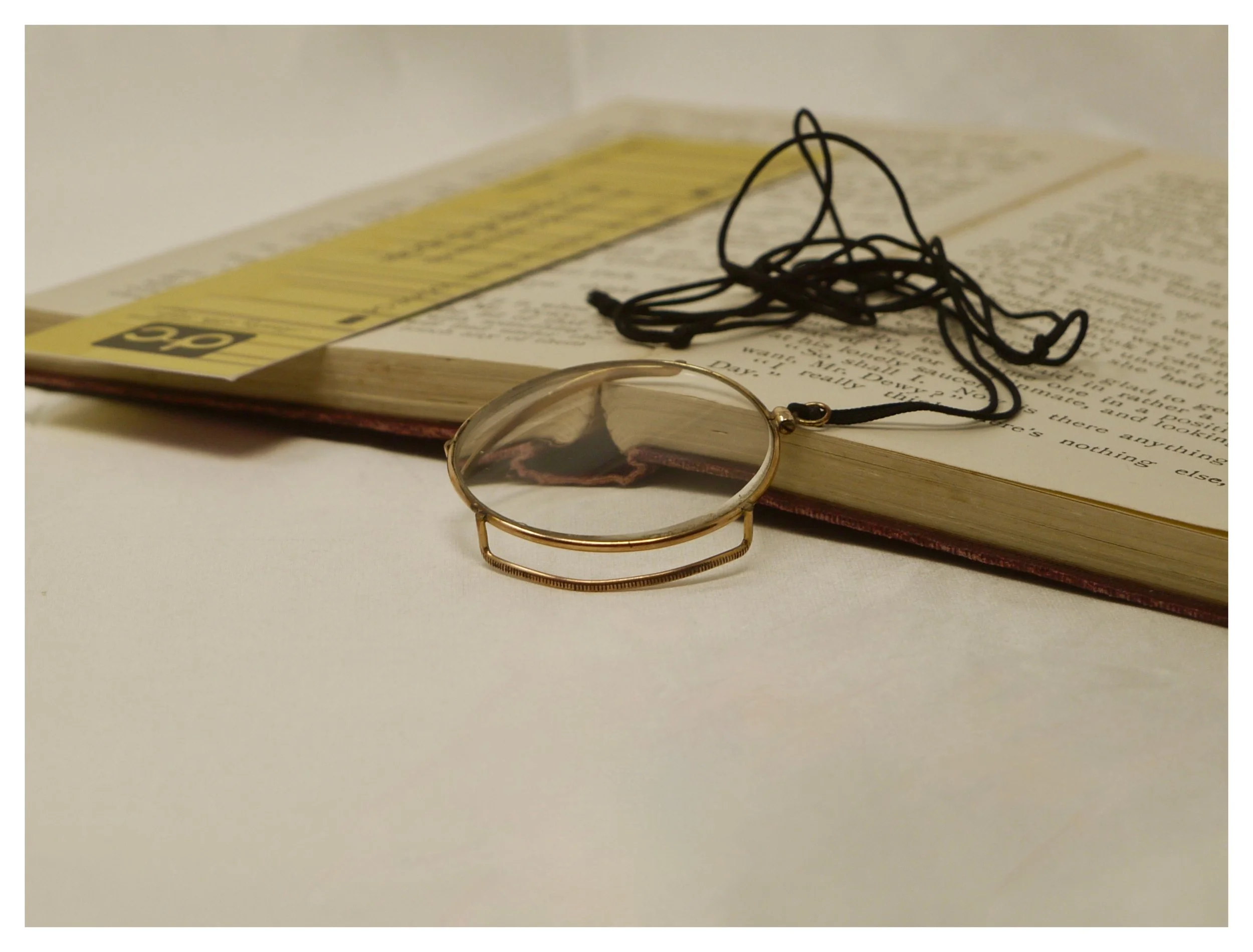 Front view of antique gilt gallery monocle balanced upright on a book spine, showing the raised edges.