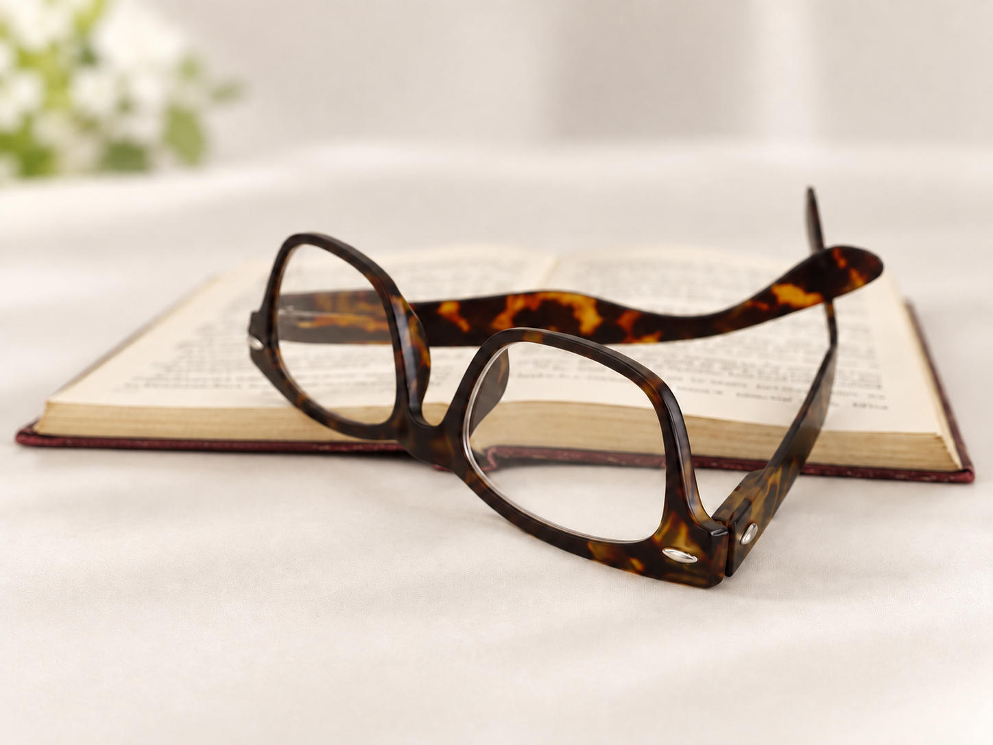 Woody tortoiseshell reading glasses resting open on the pages of a book