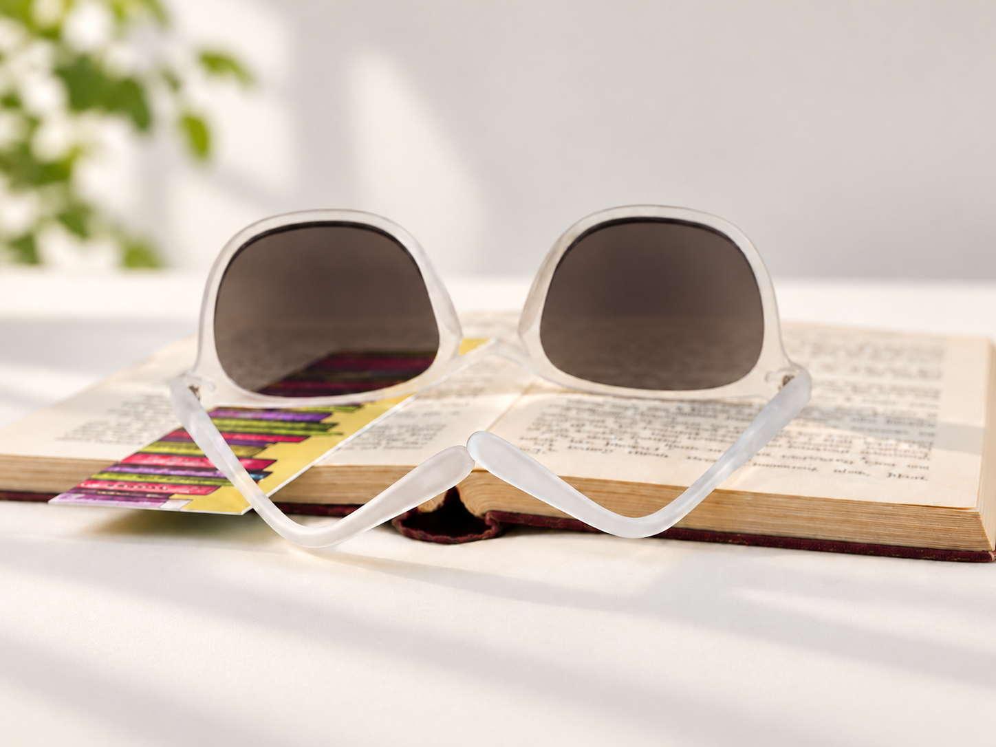 Playa Crystal sun reading glasses resting on an open book