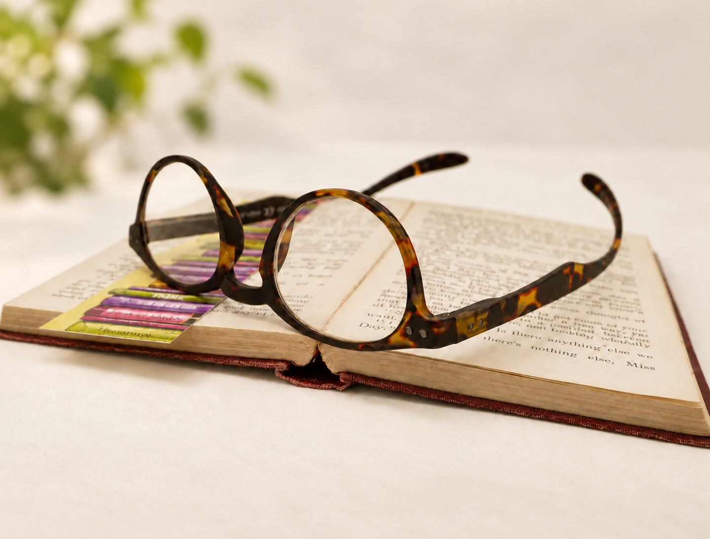 Havana Hangover Panto long-arm reading glasses resting upside down on an open book