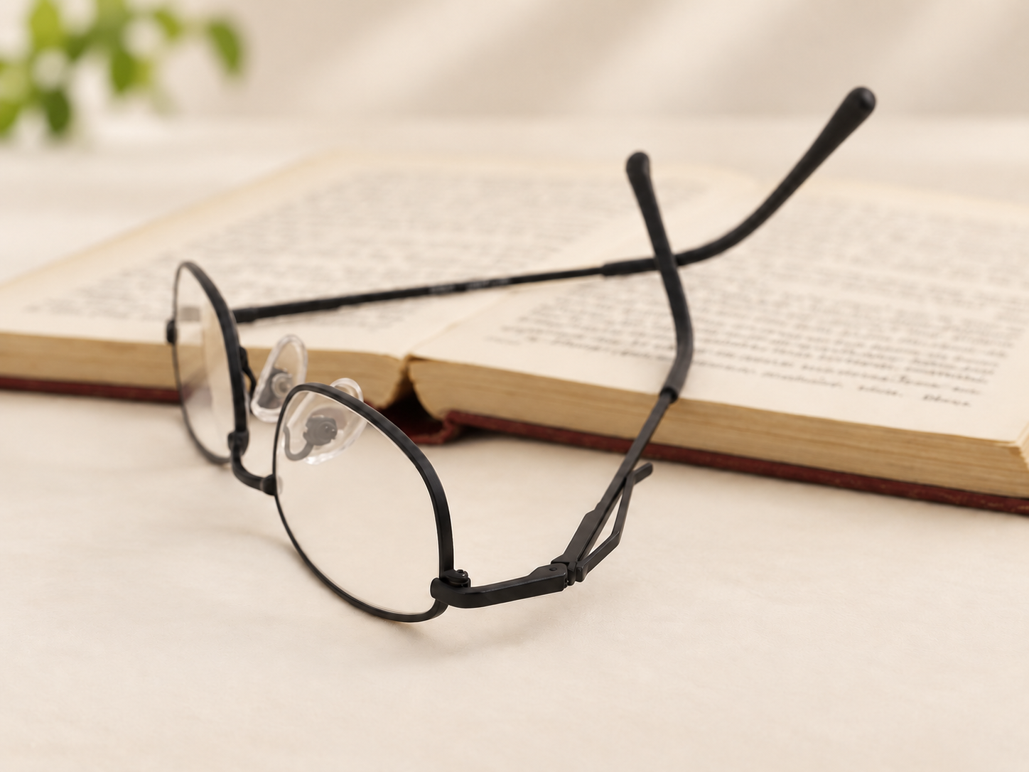 C-2204 black metal reading glasses beside an open book with the pocket clip visible