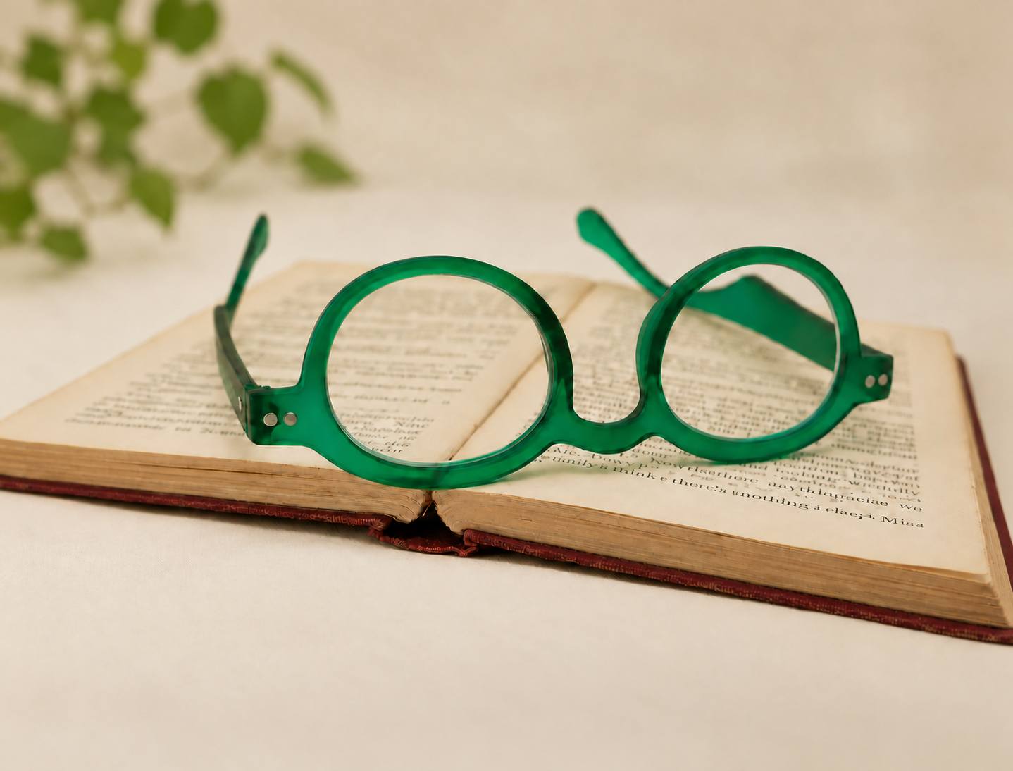 Doctor green rounded reading glasses resting open on the pages of a vintage book