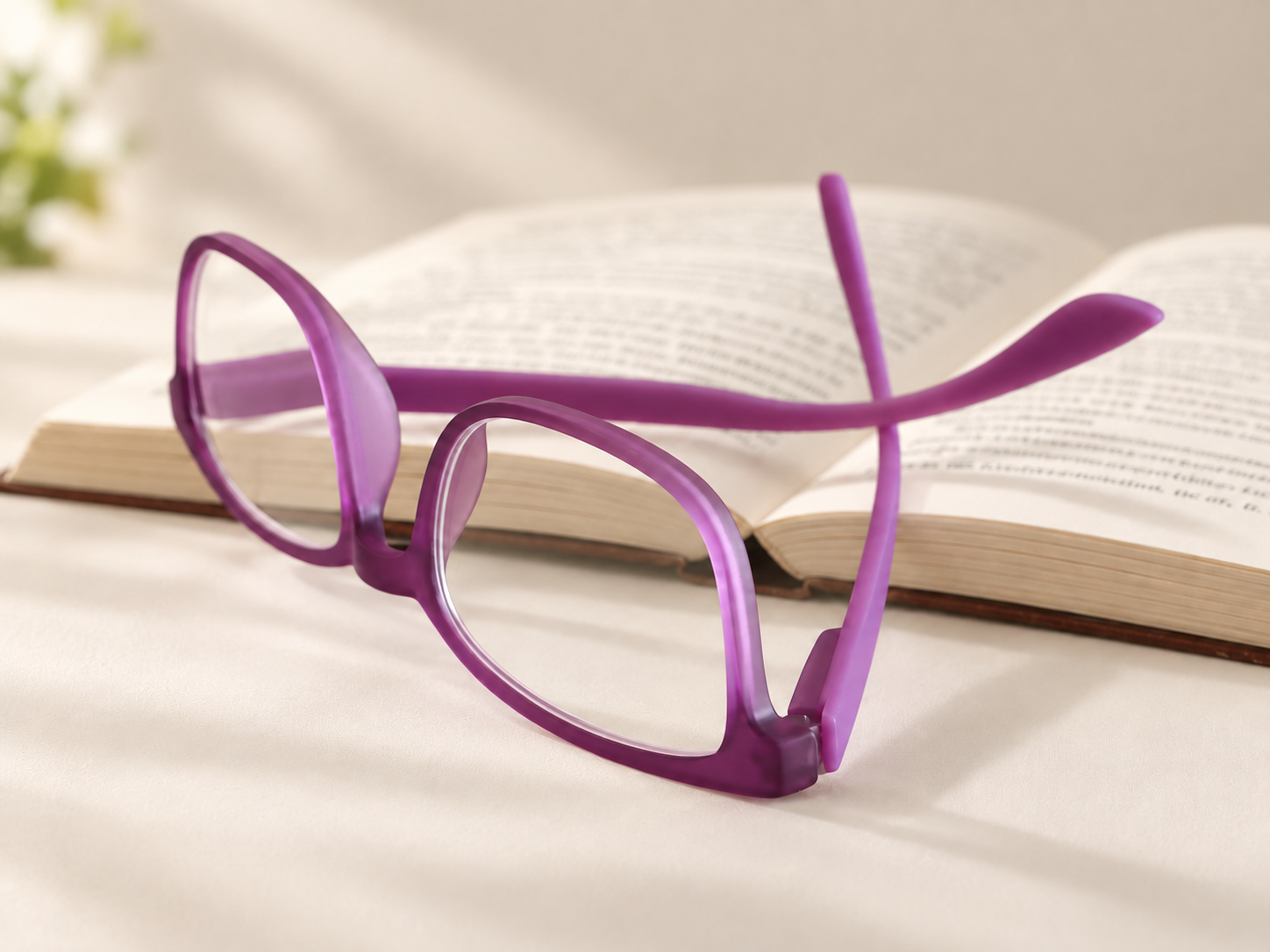 Rainbow Lilac reading glasses resting beside an open book