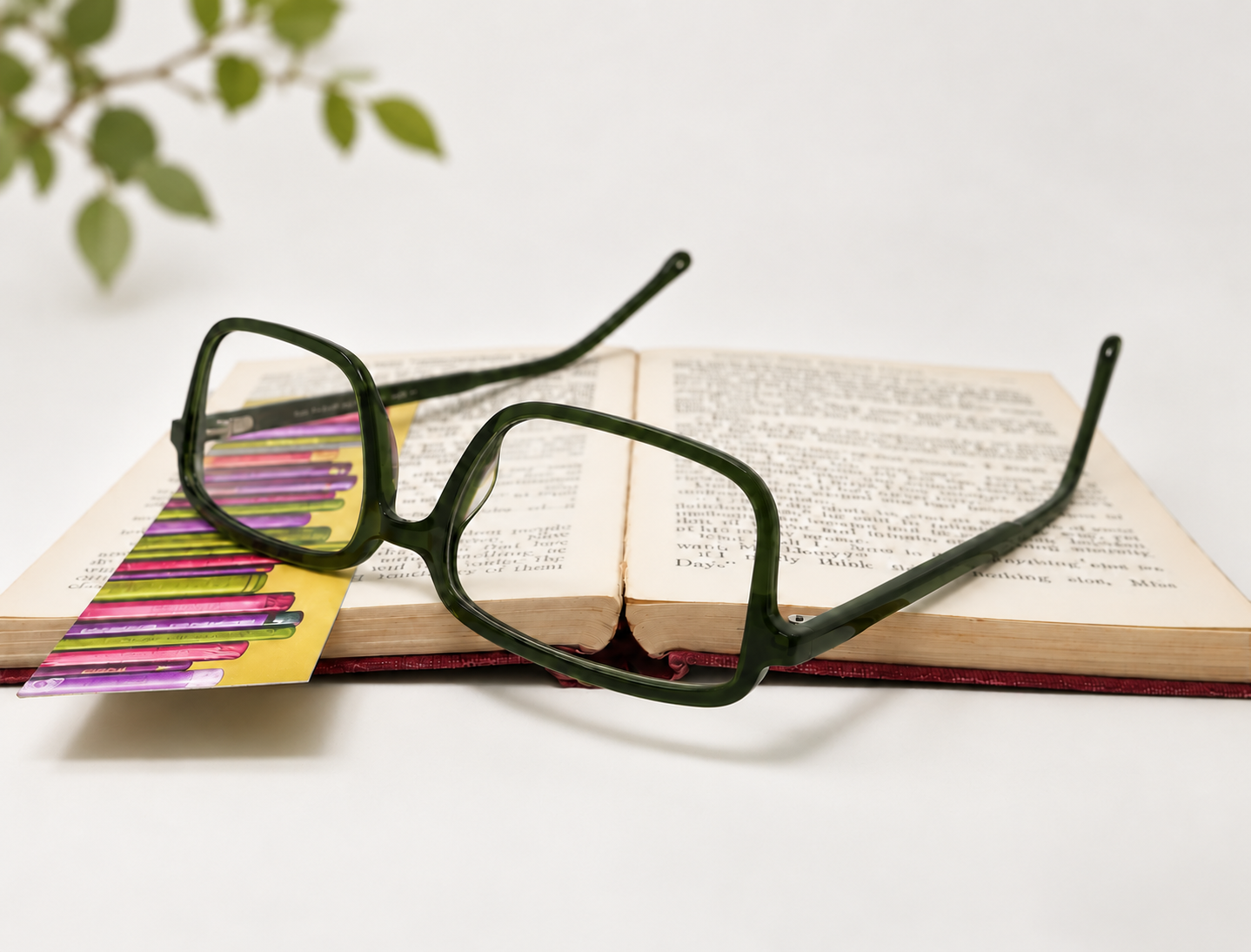 F-0641 dark green reading glasses resting upside down on an open book