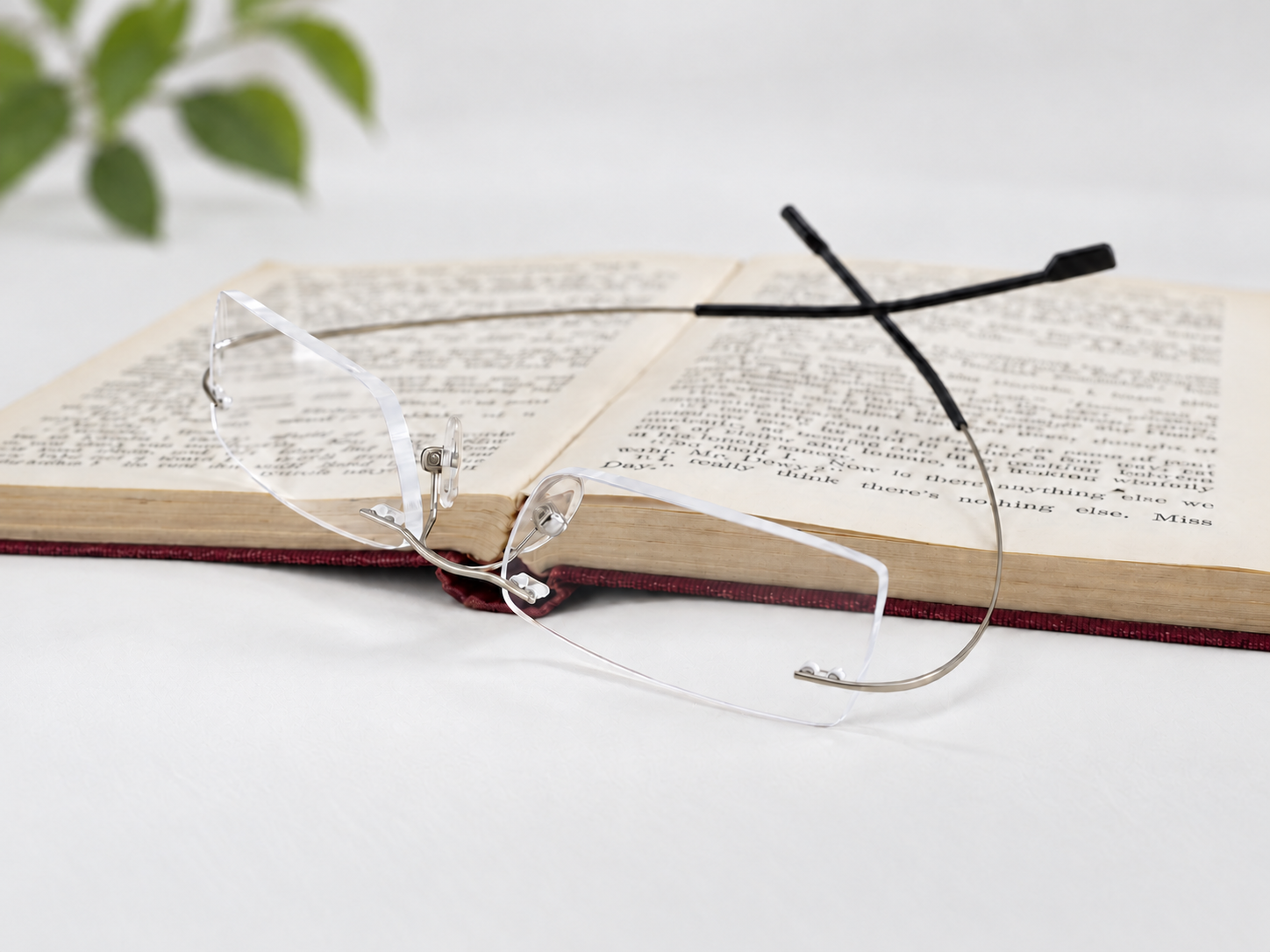 FlexiSpex 9946 silver rimless reading glasses beside an open book