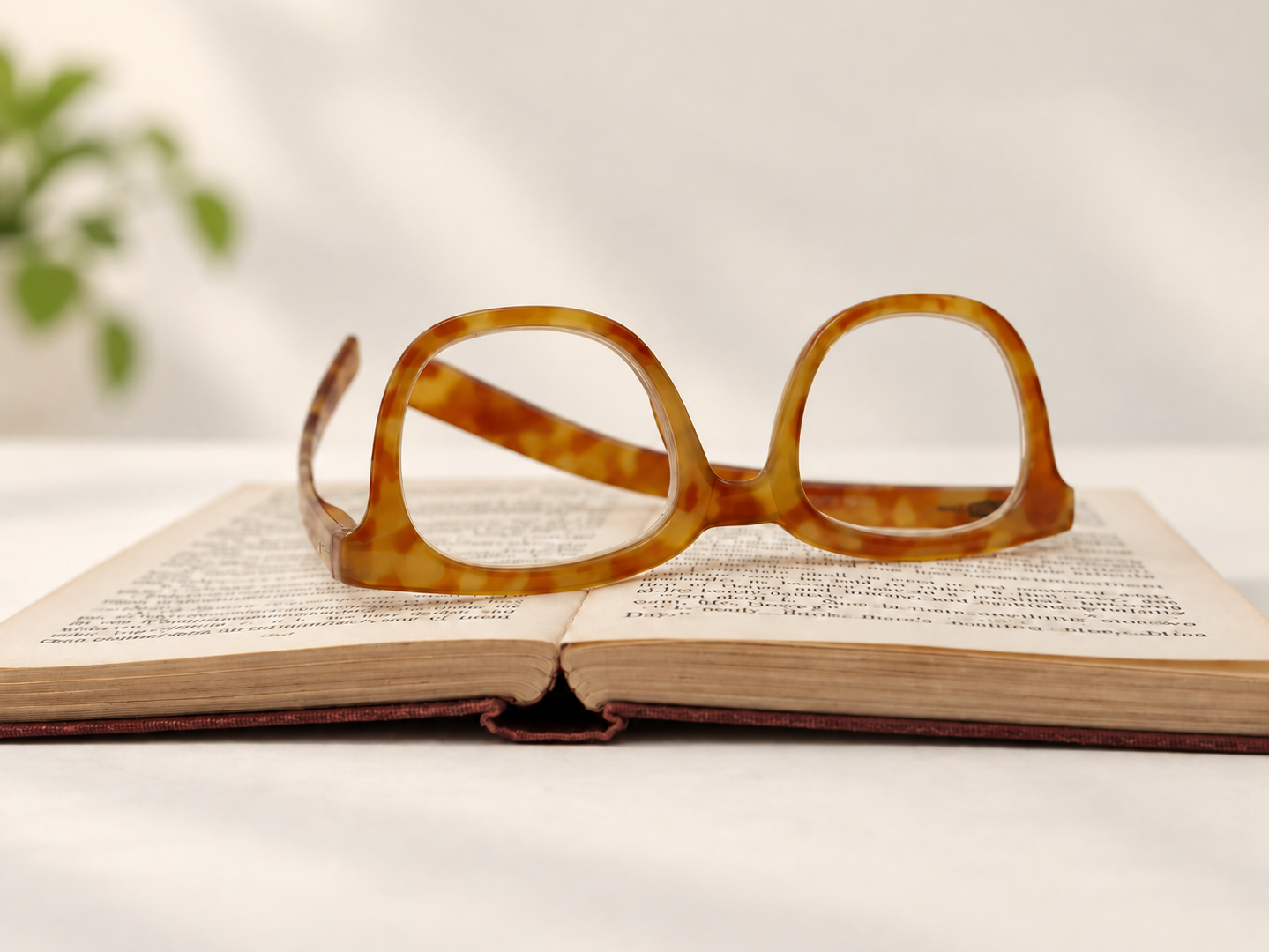 I Need You John light Havana reading glasses resting open on the pages of a book