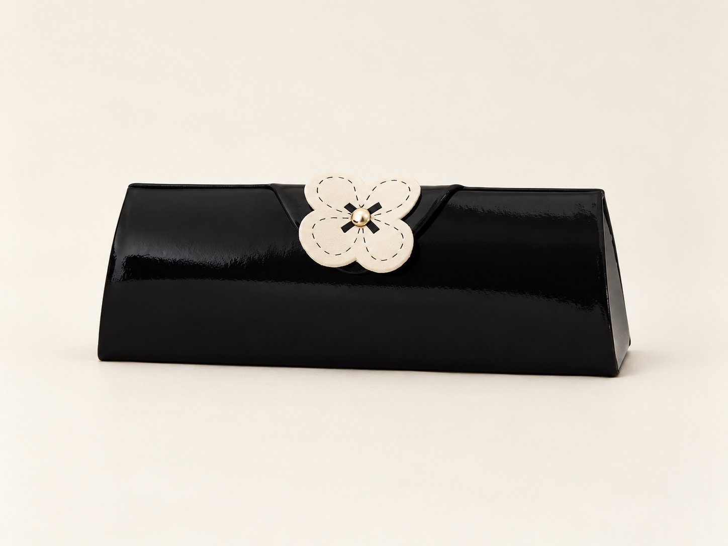 Closed black J65 spectacle case with a glossy finish and a cream flower on the front