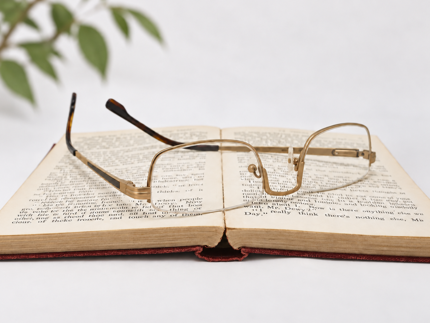 Rear view of Julian Beaumont 3659 gold reading glasses resting upside down on an open book