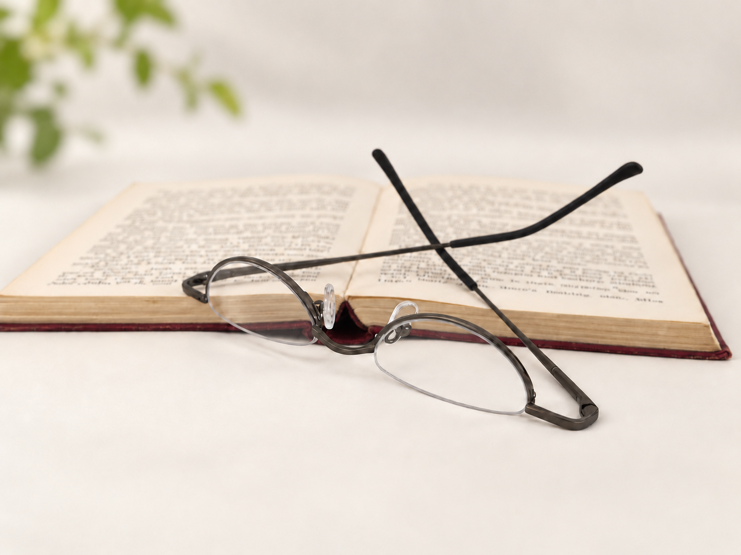 B-DCHR gunmetal half-eye reading glasses resting beside an open book
