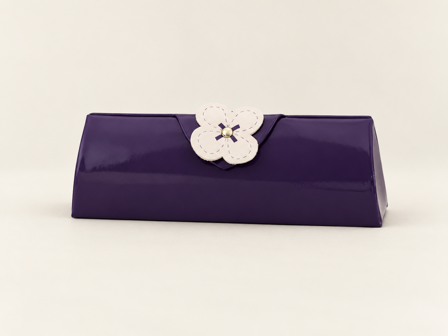 Closed purple J65 spectacle case with a glossy finish and a cream flower on the front