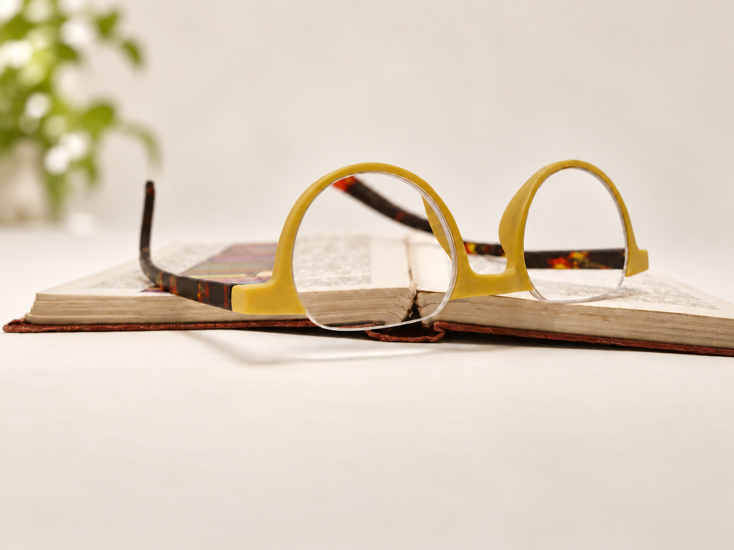 Ikaly Copenhagen pastel yellow and tortoiseshell reading glasses resting on an open book