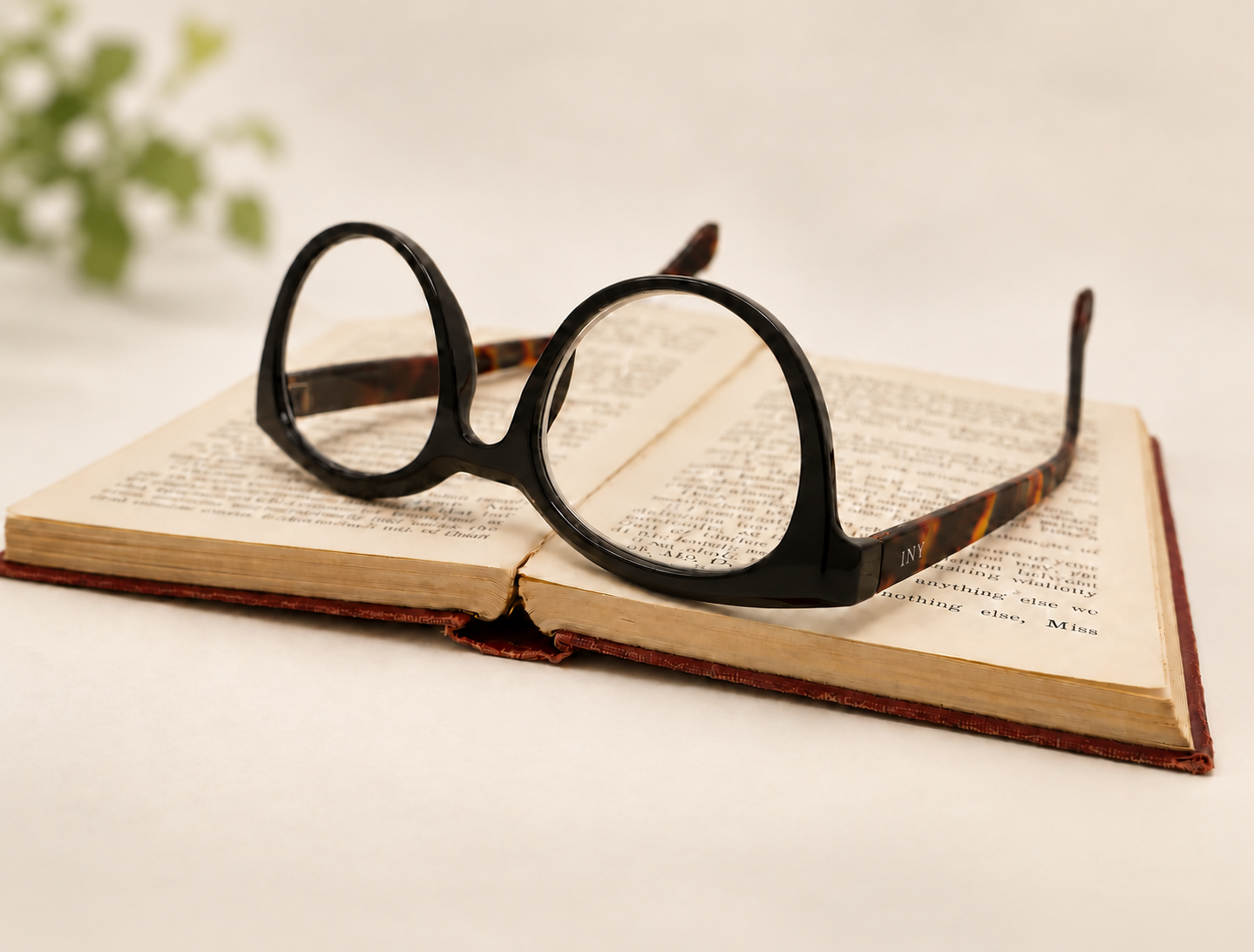 Jackie black and tortoiseshell round reading glasses resting on an open book