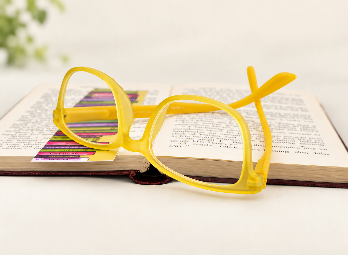 Rainbow Yellow reading glasses with translucent yellow full frame resting on an open book