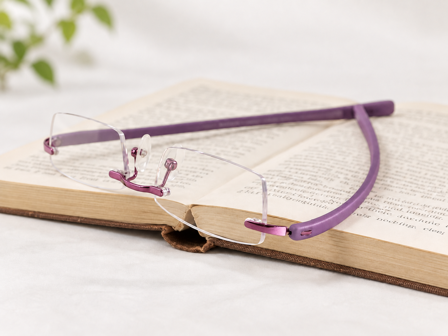 Peek purple rimless reading glasses resting on an open book