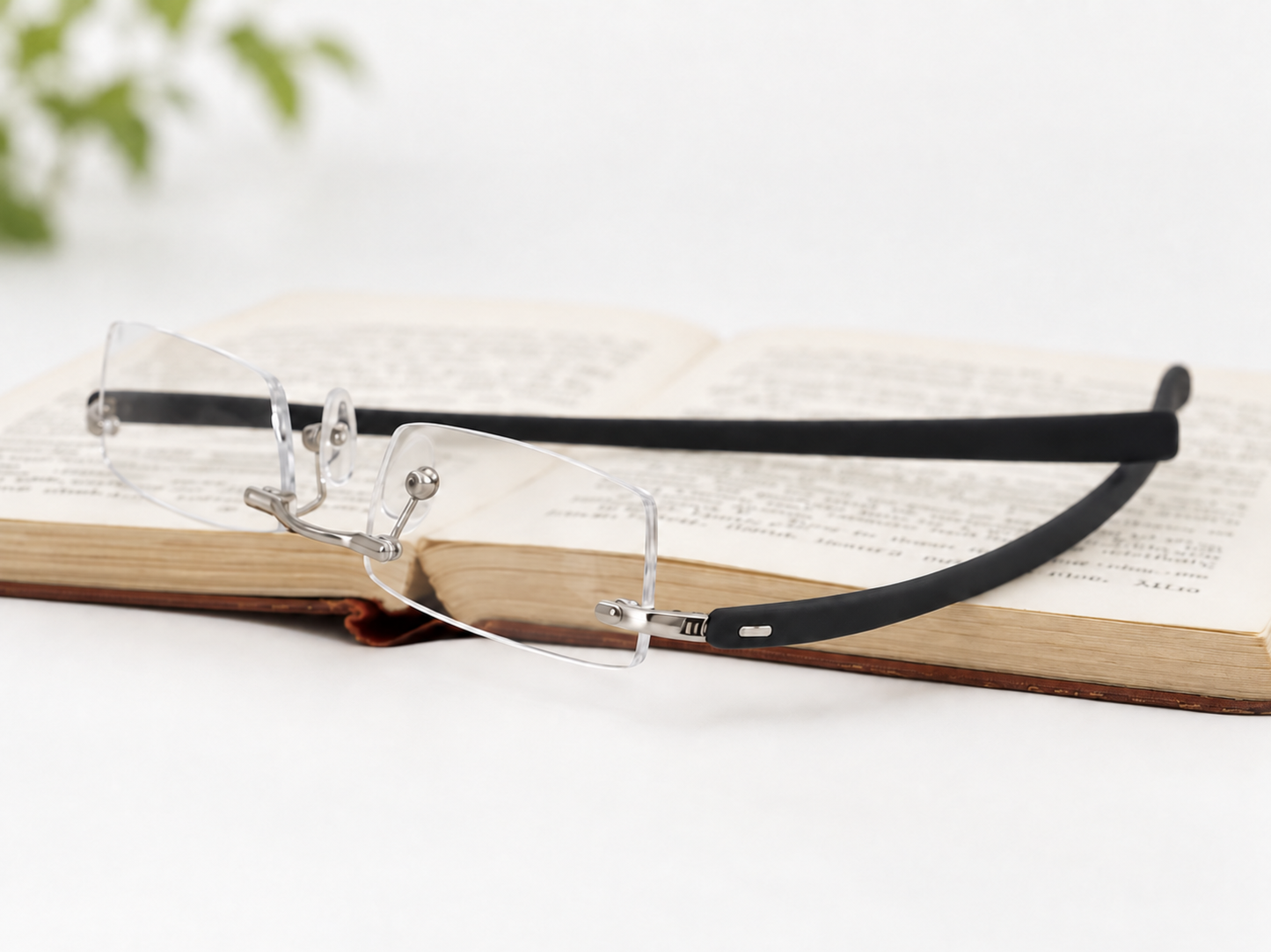 Peek Silver rimless reading glasses beside an open book