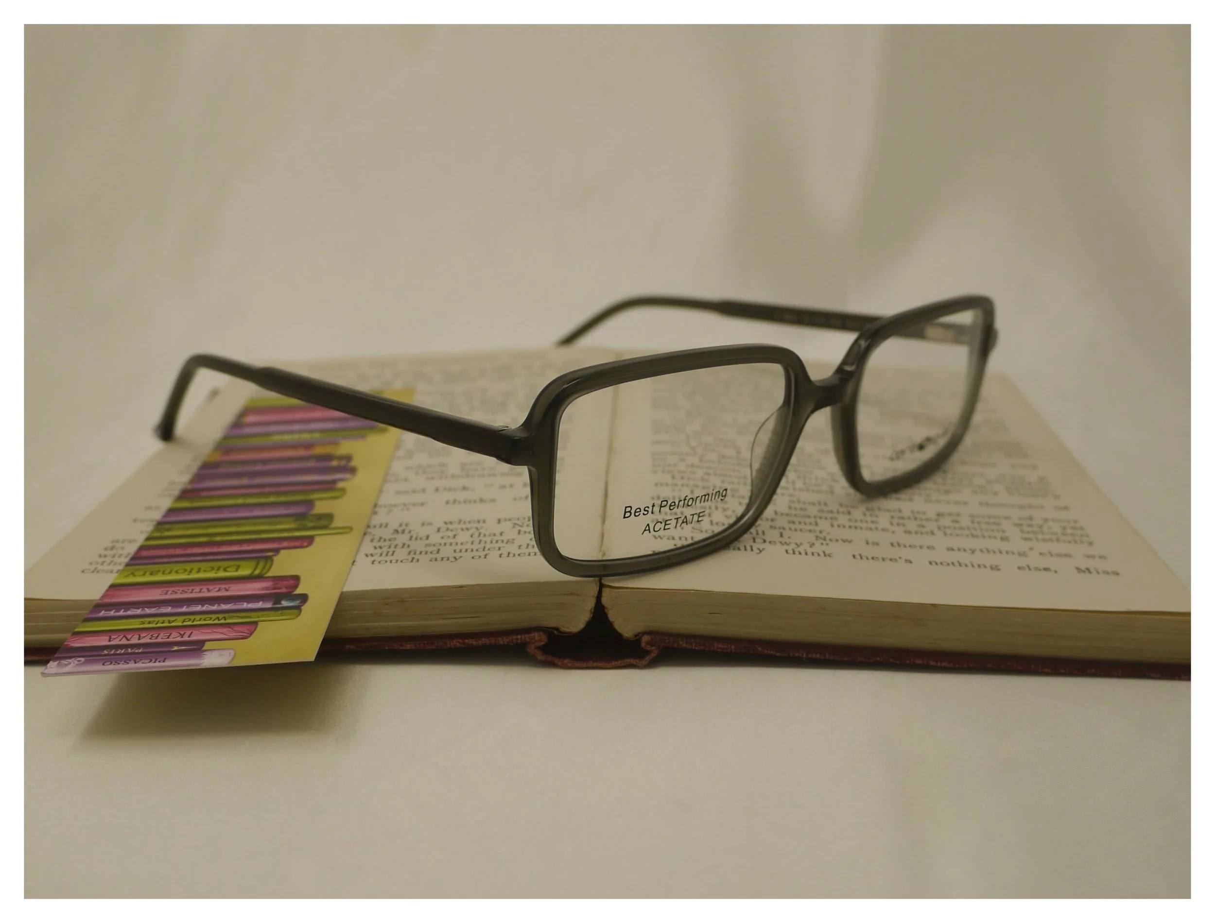 Bespoke F0641 dark green reading glasses resting on a classic Thomas Hardy novel, showcasing their refined aesthetic